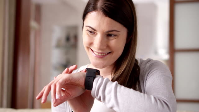 Woman-at-home-sending-audio-message-via-smart-watch.-Young-female-professional-working-on-smartwatch