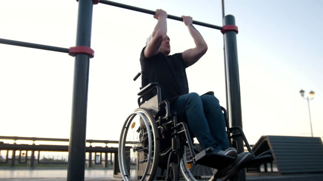 Junge-Behinderte-Mann-im-Rollstuhl-auf-die-Querlatte-im-Freien-beschäftigt