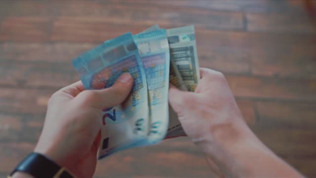 Close-up-of-hands-counting-euro-banknotes.-Stock.-Vacation,-tourism,-travel,-finances-and-people-concept---close-up-of-traveler-hands-counting-euro-cash-money
