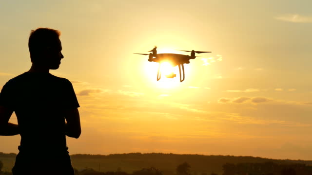 El-hombre-jugando-con-una-quadrocopter-al-fondo-puesta-de-sol