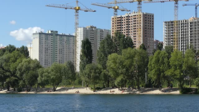 Un-lago-contra-el-fondo-de-las-casas-en-construcción.-Se-construyen-rascacielos-cerca-del-lago.-Construcción-de-edificios-residenciales-cerca-del-lago.