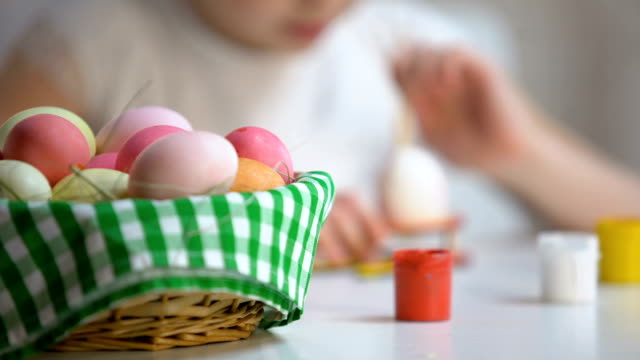 Huevo-de-pintura-creativa-littlie-chica-con-cepillo,-canasta-de-Pascua-en-la-tabla,-festival