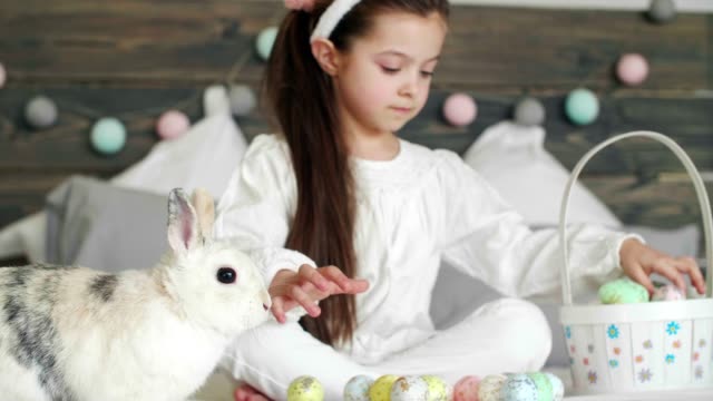 Mädchen-mit-Kaninchen-und-Ostereiern-auf-dem-Bett