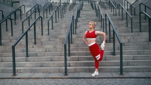Plus-size-mixed-race-blonde-smiling-woman-wearing-red-sportswear-warm-up-before-run