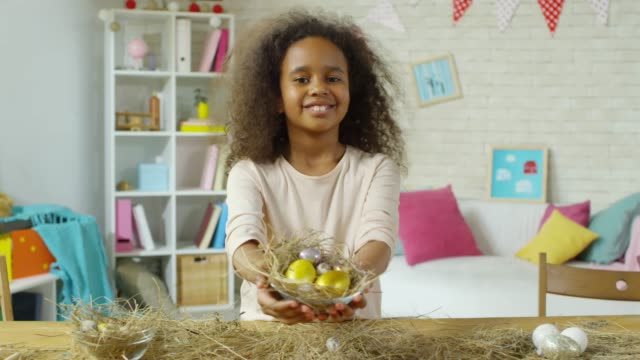 Little-African-Girl-Smiling-and-Posing-with-Easter-Eggs-in-Hay-Nest