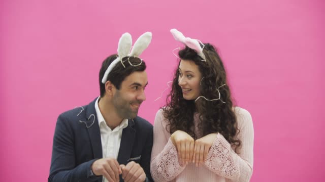 Young-sexy-couple-on-pink-background.-With-hackneyed-ears-on-the-head.-During-this-reproduction-sexual-rabbit-movements-and-looks,-after-a-while-go-out-of-the-frame.
