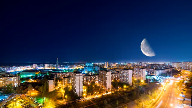 The-night-city-against-the-moon-background.-time-lapse