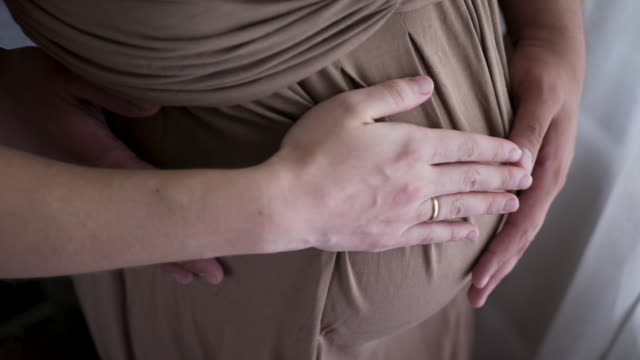 Schwangere-Frau-in-braunem-Kleid-und-ihr-Mann-in-einem-weißen-T-Shirt