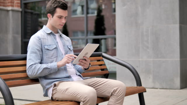 Gelegenheits-Junal-Mann-Sitting-Outdoor-und-Using-Tablet