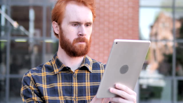 Redhead-Beard-Young-Man-Using-Tablet-Outdoor