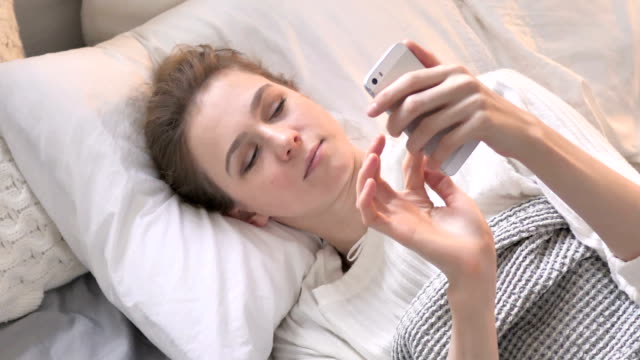 Top-View-of-Young-Woman-Using-Smartphone-in-Bed,-Browsing