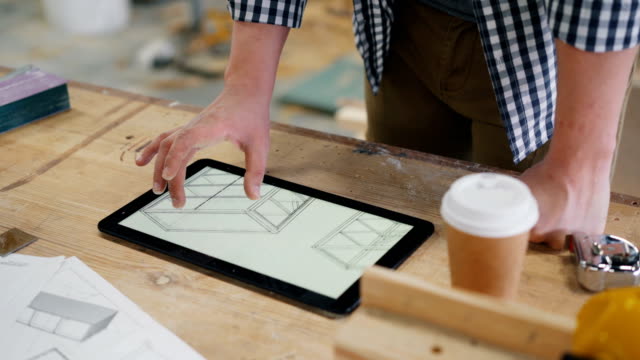 Männlicher-Zimmermann,-der-sich-technische-Zeichnungen-von-Möbeln-auf-Tablet-Bildschirm-ansieht