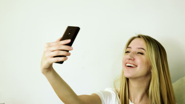 Schöne-blonde-Frau-schaut-auf-ihr-Handy,-macht-ein-Selfie-in-einem-Café.-4K