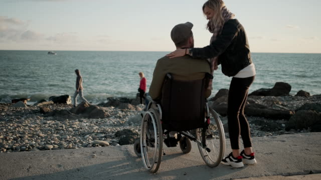 Mujer-está-abrazando-a-su-amado-marido-discapacitado-en-la-orilla-del-mar