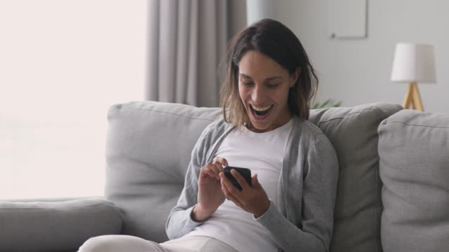 Happy-overjoyed-girl-holding-phone-celebrate-mobile-win-at-home