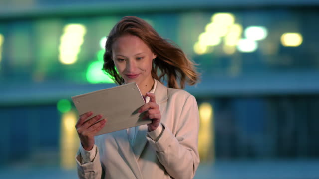 Businesswoman-using-electronic-tab-outdoors-in-the-evening