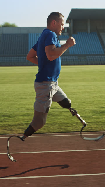 Athletic-Disabled-Fit-Man-mit-Prothetic-Running-Blades-trainiert-im-Stadion.-Amputierteläufer-Jogging-auf-der-Stadionbahn.-Motivations-Paralympics-Champion.-Vertikale-Bildschirmausrichtung-Video-9:16