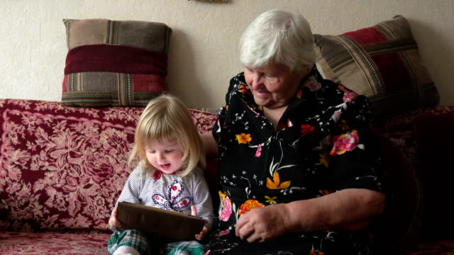 Girl-sit-with-her-grandmother-and-watch-tablet