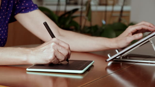 Manos-de-diseñador-femenina-utilizando-una-tableta-gráfica-de-dibujo-y-un-portátil.