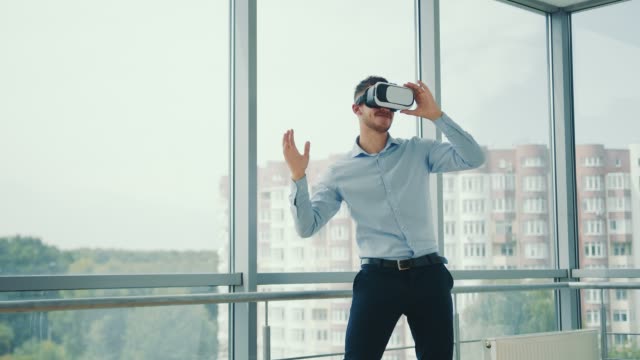 Close-up-Young-man-sitting-at-a-desk-in-the-office-uses-augmented-reality-glasses-to-work-on-business-projects-in-various-fields.-Work-in-Virtual-Reality