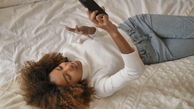 Lady-lies-on-bed-holding-smartphone-and-shooting-video-blog