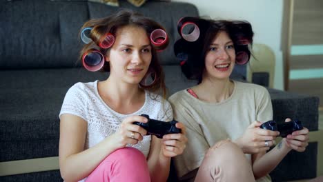 Dos-mujeres-divertidas-juegan-juegos-de-consola-con-gamepad-y-se-divierten-en-casa