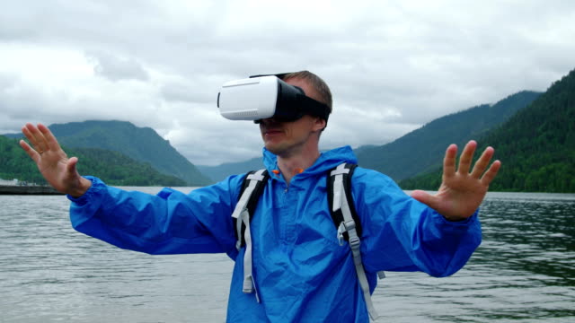A-man-uses-virtual-reality-glasses-on-the-background-of-a-mountain-lake