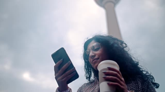Beautiful-Mixed-race-woman-using-smart-phone-technology-app-living-urban-happy-lifestyle-on-the-background-of-the-Berlin-TV-tower