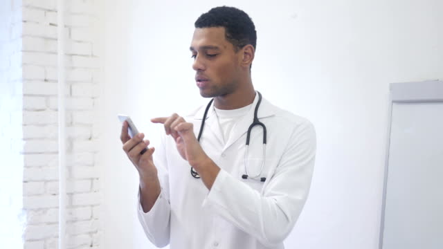 Africano-americano-Doctor-navegación-Smartphone-en-Hospital