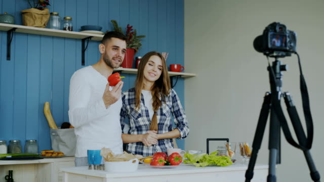 Fröhliche-attraktives-Paar-Aufzeichnung-video-Blog-über-vegetarische-Ernährung-auf-Dslr-Kamera-in-der-Küche-zu-Hause