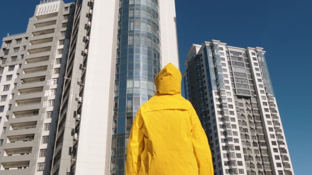 Jemand-im-gelben-Regenmantel-vor-modernes-Wohngebiet-Gebäude-bleiben