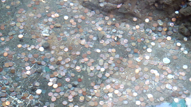 Coins-on-the-bottom-of-a-wishing-well-fountain-in-slow-motion