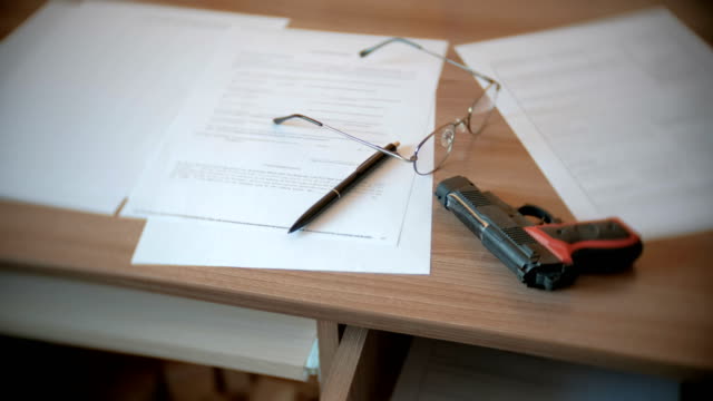 Testament,-pen,-glasses,-and-gun-on-the-table.