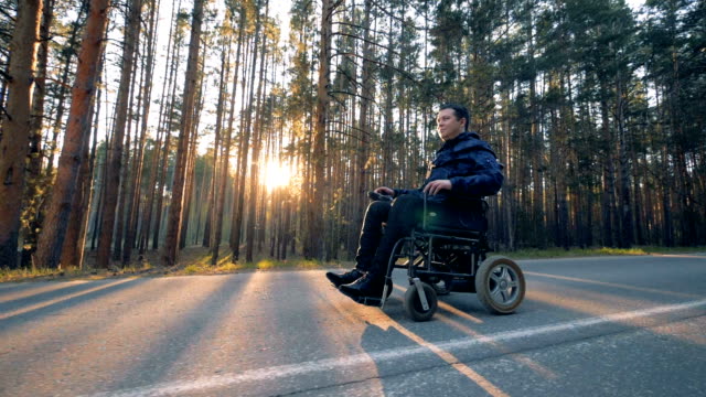 Disabled-man-is-slowly-moving-on-his-powered-wheelchair-along-the-alley