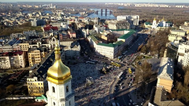 A-bird's-eye-view,-panoramic-video-from-the-drone-in-FullHD-to-the-Saint-Sophia's-Cathedral,-Sofiyivska-Square,-left-bank-of-city-in-the-city-of-Kiev,-Ukraine.-People-on-the-square-on-Easter-days.
