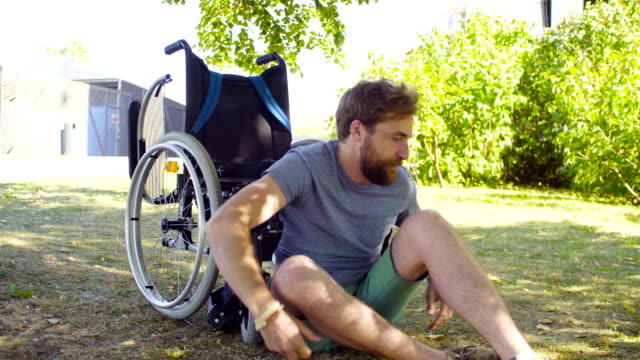 Young-disable-man-trying-to-sit-down-in-a-wheelchair