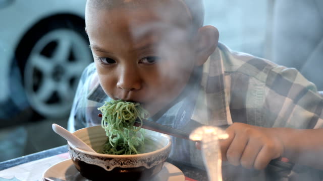 happy-child-eating-delicious-noodle-in-restaurant.-Asian-boys-who-have-vision-disabilities.-Left-eye-is-not-visible-from-brain-surgery.-Come-back-to-normal-life-Effect-of-the-treatment.-New-life
