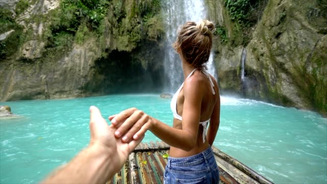 Follow-me-to-concept-young-woman-leading-boyfriend-to-amazing-waterfall,-shot-in-Cebu-Island,-Visayas-Islands,-Philippines.-Idyllic-tropical-travel-journey-vacations-concept.-Slow-motion-video