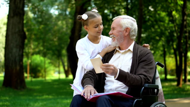 Handicapped-grandpa-showing-to-granddaughter-family-photos-telling-about-granny