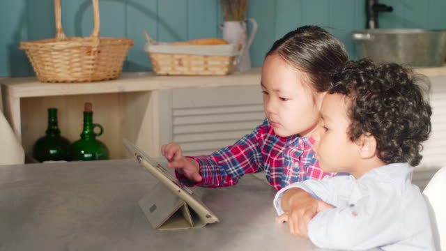 Niña-asiática-y-africano-niño-usando-la-tableta-juntos