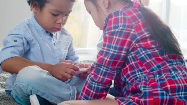 Multiethnische-Kinder-spielen-auf-Smartphone-auf-Bett