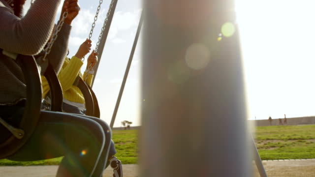 Happy-couple-playing-on-playground-swing-in-the-park-4k