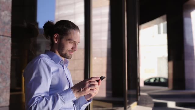 Business-Man-Using-Mobile-Phone-Near-Office-Building