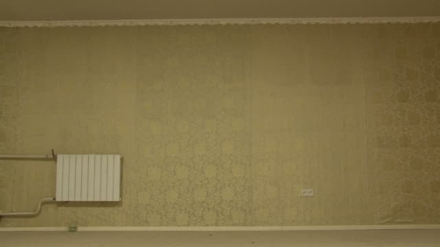 Wand-mit-goldener-Tapete-im-Vintage-Stil-in-einem-leeren,-unmöblierten-Zimmer