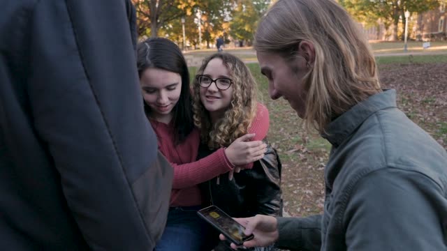 Zwei-junge-Frauen,-die-ihre-Arme-umeinander-tragen,-sitzen-außerhalb-des-College-Campus