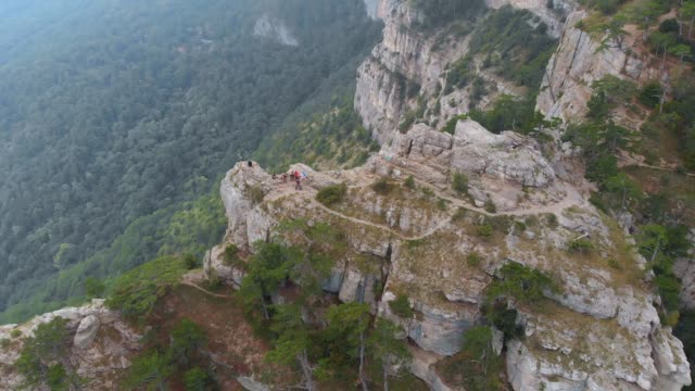 Luftbild:-Touristen-sitzen-am-Sommertag-auf-der-Bergklippe