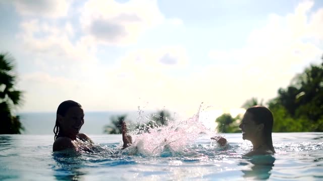 Dos-chicas-jugando-en-la-piscina-al-aire-libre-en-un-día-soleado