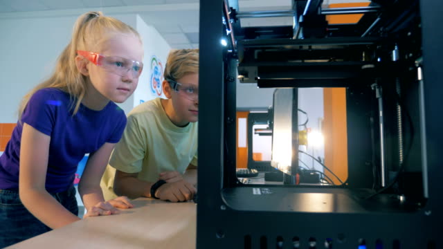Niños-de-la-escuela-excitados-usando-impresora-tridimensional-para-crear-robot-impreso-en-3D.