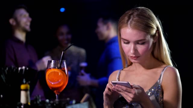 Single-elegant-female-using-phone-in-night-club