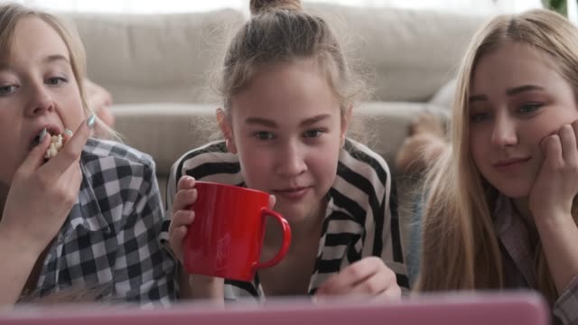 Mädchen-beobachten-Medieninhalte-auf-dem-Laptop,-während-sie-Essen-und-Trinken-haben